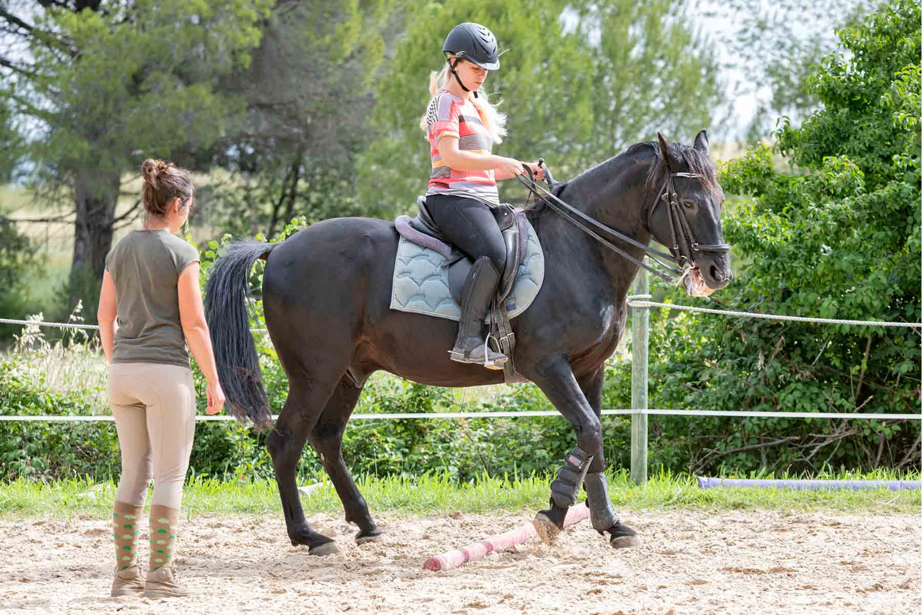 An equestrian instructor giving a woman horseback riding lessons.