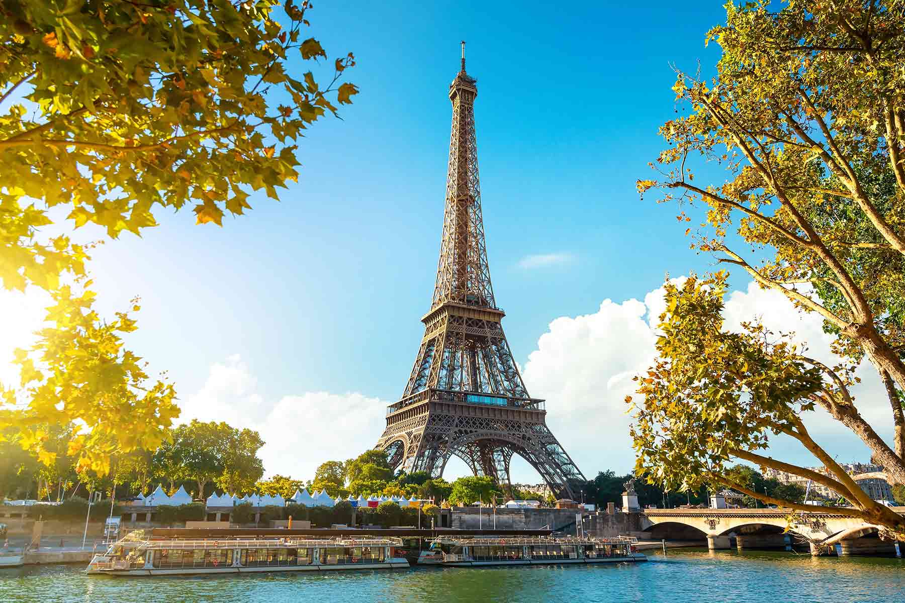 World famous Eiffel tower under a colorful sky and green trees