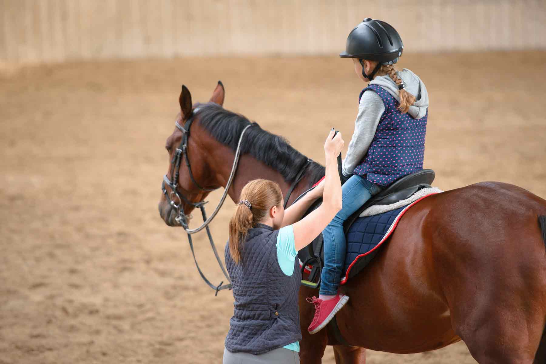 An instructor giving a young girl private horse riding lessons.