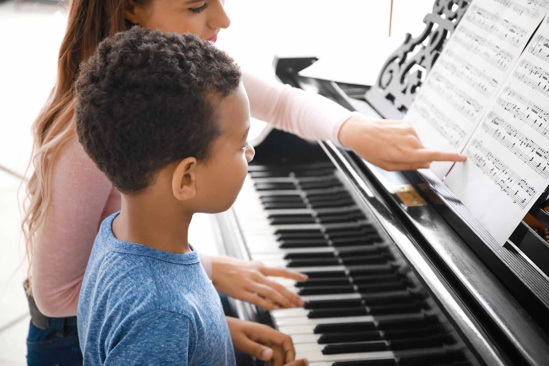 A piano teacher giving lessons to a young boy.