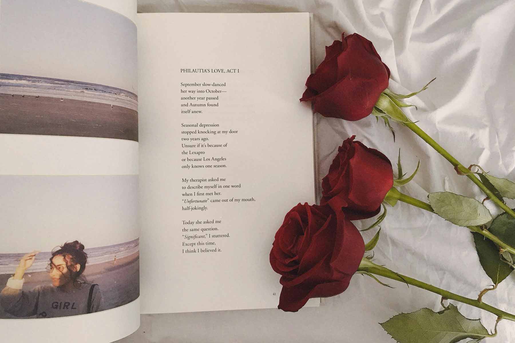 An open book of poems next to red roses