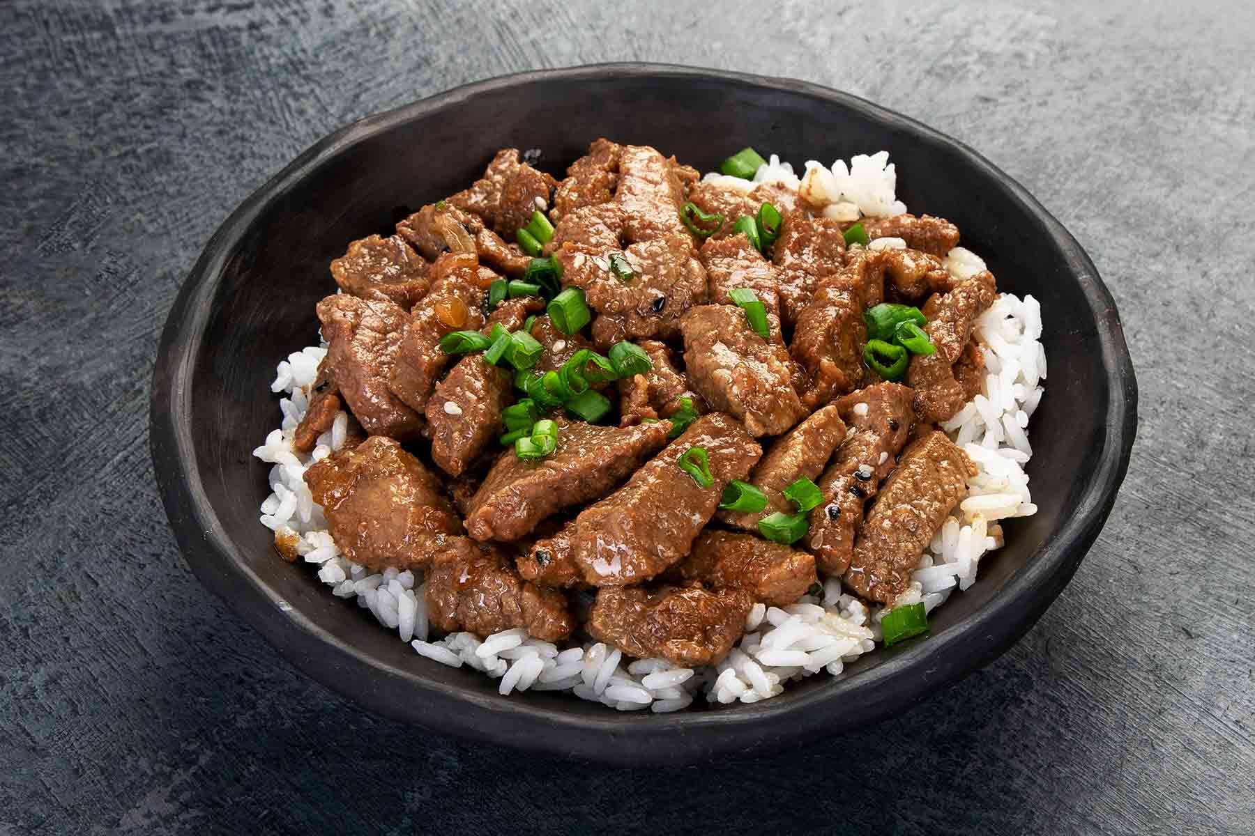 A close-up bowl of Korean beef bulgogi served over steamed rice