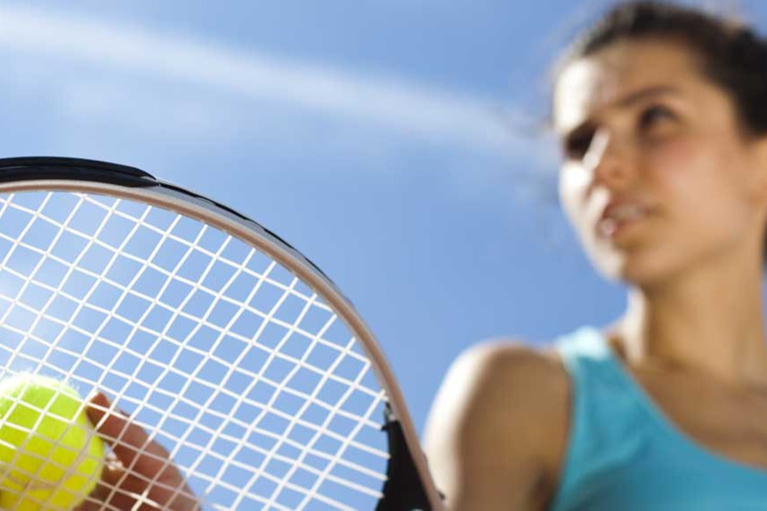 Young woman learning to serve during tennis lesson